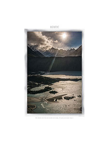 Ray of sunshine briefly appears over body of water in hills.